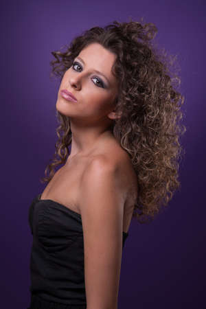young and beautiful woman, with curly hair, on purple background, studio shotの写真素材