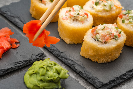 hold ginger next to sushi with chinese wooden chopsticksの写真素材