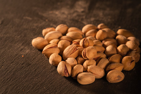 a handful of salted pistachios lies on a black tableの写真素材