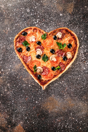 Heart shaped not ready pizza with tomatoes and mozzarella for Valentines Day on vintage concrete background. Food concept of romantic loveの写真素材
