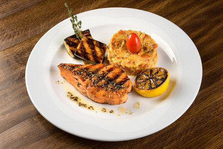 Teriyaki salmon with zucchini and lemon on white plateの写真素材