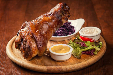 Roasted knuckle of pork with boiled cabbage, horseradish and mustard on wooden backgroundの写真素材