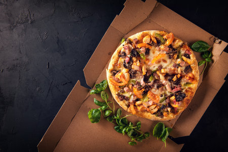 Cut into slices delicious fresh pizza with mushrooms and pepperoni on a dark background. Top view . Pizza on the black table.の写真素材