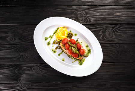 Grilled trout with tomatos leguminous beans and lemon on white plate. Top viewの写真素材