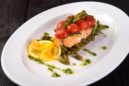 Grilled trout with tomatos leguminous beans and lemon on white plate. close upの写真素材