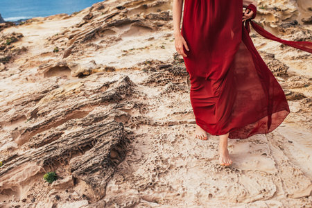 Girl in red dress among rocks and cliffs along the Coast of Algarveの写真素材