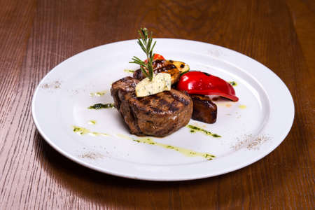 thick steak with rosemary and fried vegetables cheese on white plateの写真素材