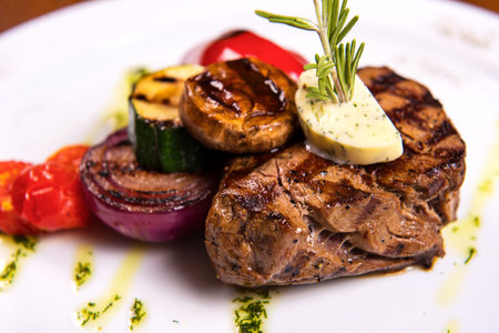 thick steak with rosemary and fried vegetables cheese on white plate. close upの写真素材