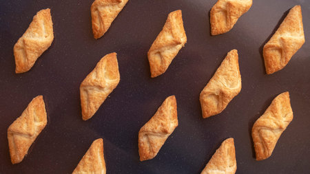 Cookies in the shape of a triangle on a baking sheet.
