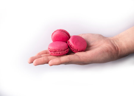 Hand holding pink macaroon on white background. isolated.の写真素材
