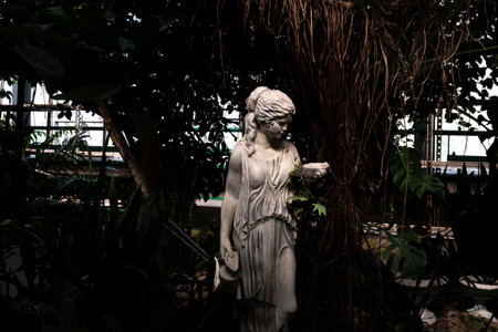 Statue of a woman with a flower in her hand in the gardenの写真素材
