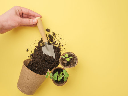 A set of gardening tools on a yellow background. The earth pours out of the pot. View from above....