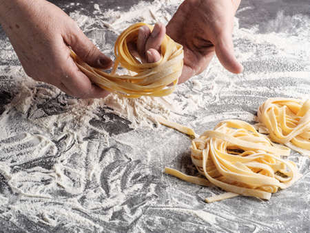 A woman rolls homemade Italian fettuccine pasta.の写真素材