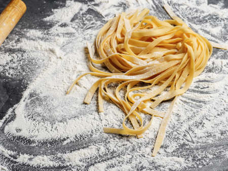 Homemade Italian fettuccine pasta sprinkled with flour on the table.の写真素材