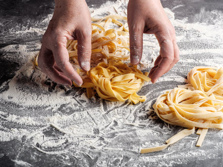 A woman rolls homemade Italian fettuccine pasta.の写真素材