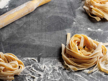 Homemade Italian fettuccine pasta sprinkled with flour on the table.の写真素材