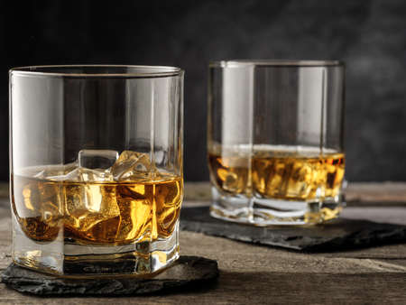 Two glasses of whiskey stand on an old wooden table. Horizontal photo. Copy space.の写真素材