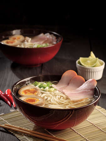 Two bowls of hot pork ramen and pickled eggs that steamed. Vertical photo.の写真素材