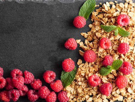 Granola, raspberries, peppermint leaves lie on a stone, copy space, top view.の写真素材