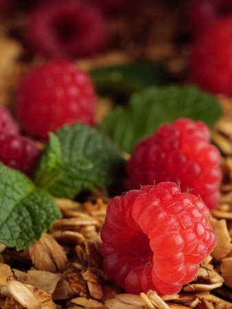 Raspberries lie on granola with mint leaves. Vertical photo.の写真素材