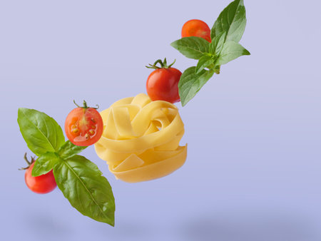 Flying in the air, raw fettuccine pasta with cherry tomatoes and basel leaves. Colored isolated.