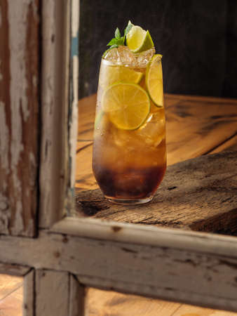 Classic cocktail Cuba Libre on a wooden table, copy space.の写真素材