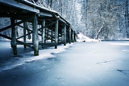 Winter landscape. Old wooden bridge under river.の写真素材