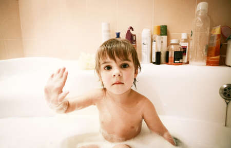beautiful child washing in bubble domestic bath の写真素材