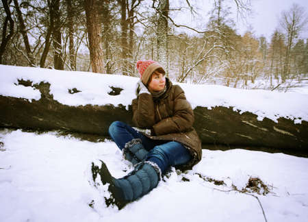 winter girl in the  forest sitting in the snow の写真素材