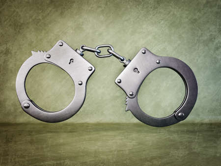steel handcuff isolated on a green backgroundの写真素材