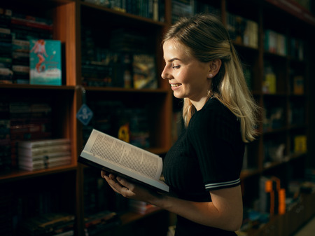 A young student reads a very interesting book in the libraryの写真素材