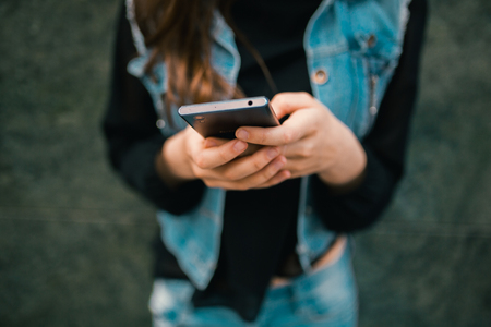 Beautiful teens talk to smartphone dressed in jeans, and have fun in the cityの写真素材