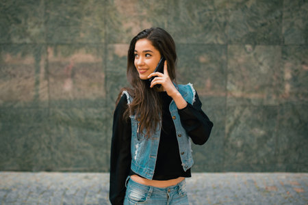 Beautiful teens talk to smartphone dressed in jeans, and have fun in the cityの写真素材