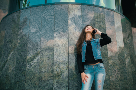 Beautiful teens talk to smartphone dressed in jeans, and have fun in the cityの写真素材