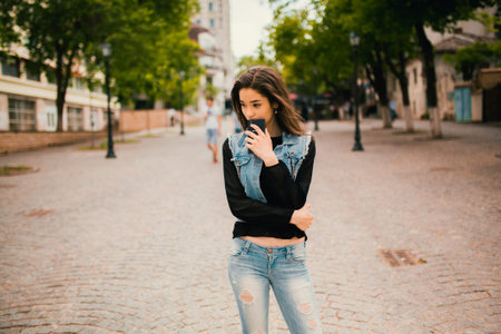 Beautiful teens talk to smartphone dressed in jeans, and have fun in the cityの写真素材