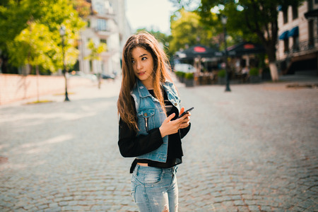 Beautiful teens talk to smartphone dressed in jeans, and have fun in the cityの写真素材
