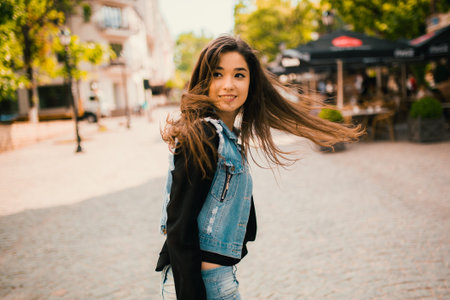 Beautiful teens talk to smartphone dressed in jeans, and have fun in the cityの写真素材