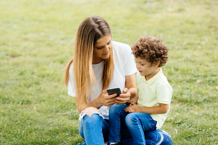 Mother and her baby, play cheerfully in the smartphone, outdoorsの写真素材