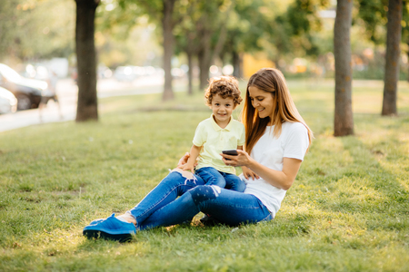 Mother and her baby, play cheerfully in the smartphone, outdoorsの写真素材