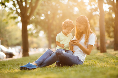 Mother and her baby, play cheerfully in the smartphone, outdoorsの写真素材