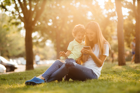 Mother and her baby, play cheerfully in the smartphone, outdoorsの写真素材