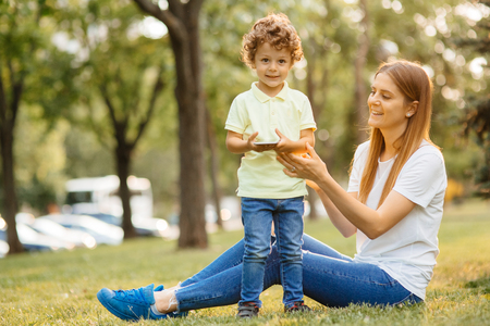 Mother and her baby, play cheerfully in the smartphone, outdoorsの写真素材