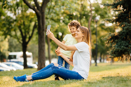 Mother and her baby, play cheerfully in the smartphone, outdoorsの写真素材