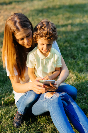 Mother and her baby, play cheerfully in the smartphone, outdoorsの写真素材