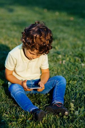 Young boy playing in smartphone, outdoorsの写真素材