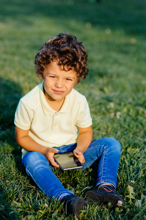 Young boy playing in smartphone, outdoorsの写真素材