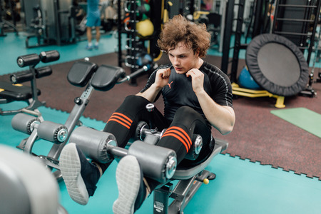 Fitness man doing exercises for the swing press. Side view of young man in sportswear isolated on white background. Strength and motivation.の写真素材