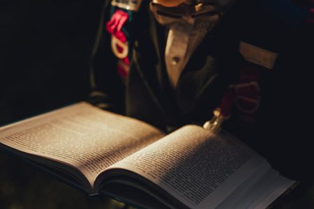 close-up, schoolgirl reads a book in the park, in a school uniform with a school bag, outdoor, at sunsetの写真素材