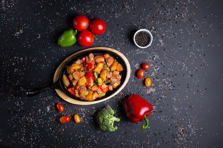 stew served in restaurant, beautifully decorated, on black background, with tomatoes, red green peppers and broccoli, top viewの写真素材