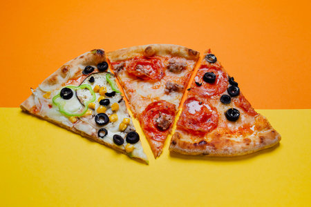 Different slices of pizza,  Delicious fresh Italian pizza, yellow and orange background, sliced...